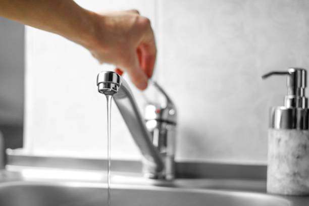 Hand opens the water tap. Close up.